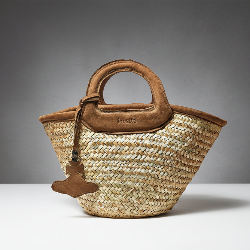 Woven straw handbag with brown leather handle and trim on a white background